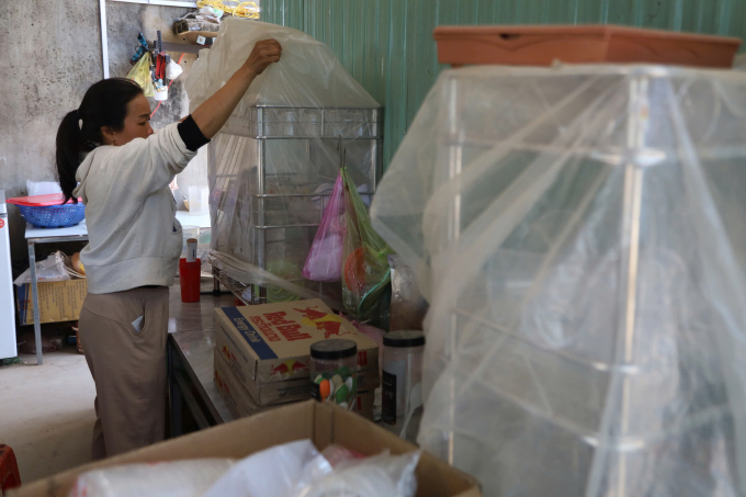 Chị Hương dùng nylon phủ kín giá để ly, chén ngăn bụi. Ảnh: Trần Hóa